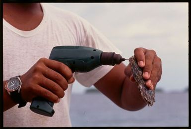 Man drilling a hole in an oyster shell, Manihiki, Cook Islands