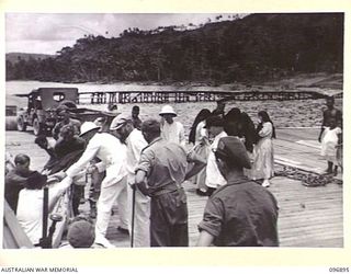 TOBOI WHARF, NEW BRITAIN. 1945-09-16. A PARTY OF MISSIONARY SISTERS AND PRIESTS FROM THE RAMALE MISSION BEING ASSISTED ONTO THE WHARF FROM THE MOTOR LAUNCH GLORIA, OPERATED BY 16 SMALL SHIPS ..