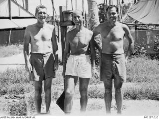 Madang, New Guinea, 1945-08-15. Informal outdoors portrait of three officers serving with Headquarters, RAAF Northern Command (NORCOM). The men, dressed only in shorts, are (left to right): Flight ..