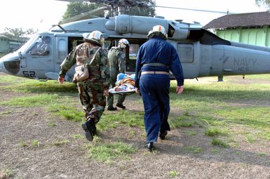 US Navy (USN) personnel carry an Indonesian patient to a USN MH-60S Seahawk helicopter, Helicopter Combat Support Squadron 5 (HC-5), Andersen Air Force Base (AFB), Guam, for a medical evacuation flight from Tentera Nasional Indonesia Military Hospital, Banda Aceh, Indonesia, to the Military Sealift Command (MSC) Hospital Ship USNS MERCY (T-AH-19) [not shown] for treatment. The MERCY is currently off the waters of Indonesia in support of Operation UNIFIED ASSISTANCE the humanitarian relief effort to aid the victims of the Tsunami that struck Southeast Asia on December 26, 2004