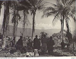 MALMAL VILLAGE, NEW BRITAIN. 1944-12-25. NX148713 CHAPLAIN R. F. A. SMYTH, ROMAN CATHOLIC HEADQUARTERS, 5TH DIVISION CELEBRATING CHRISTMAS DAY MASS IN THE JUNGLE OVERLOOKING JACQUINOT BAY