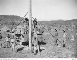 PORT MORESBY, NEW GUINEA. 1943-08-05. MEMBERS OF THE 26TH AUSTRALIAN LINE SECTION, NEW GUINEA LINES OF COMMUNICATIONS, SIGNALS, ERECTING A TELEGRAPH POLE AT HEADQUARTERS, NEW GUINEA FORCE. LEFT TO ..