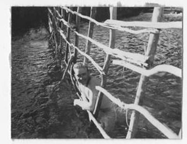 [Man in Water with Head Through a Fence]