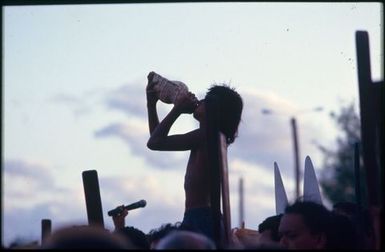 Young man blowing conch shell