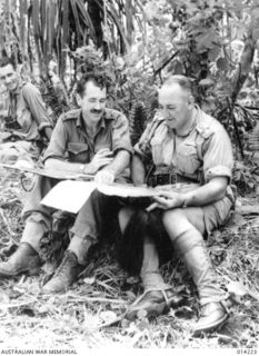 Nearing the end of the Papuan campaign against Japan. NX7 Brigadier George Frederick Wootten and Major James Alastair Yates 'Chips' Denniston, studying a map at Sanananda