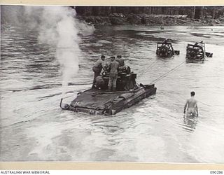 BOUGAINVILLE. 1945-03-30. TWO BULLDOZERS TOWING A B SQUADRON, 2/4 ARMOURED REGIMENT MATILDA TANK THROUGH THE PURIATA RIVER AFTER IT HAD BECOME BOGGED IN THE SOFT SAND BOTTOM