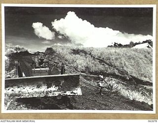 LAKE ROAD, FINISTERRE RANGES, NEW GUINEA. 1943-12-21. A BULLDOZER OF THE ROYAL AUSTRALIAN ENGINEERS, 7TH AUSTRALIAN DIVISION BEING USED TO FORM A ROAD ABOVE THE LAKE IN THE FOOTHILLS OF THE ..