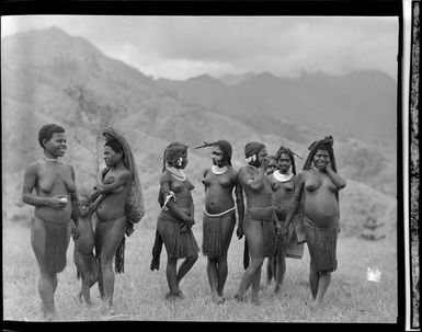 Group of unidentified locals at the Kerowagi airfield, Papua New Guinea, featuring traditional jewellery and clothing
