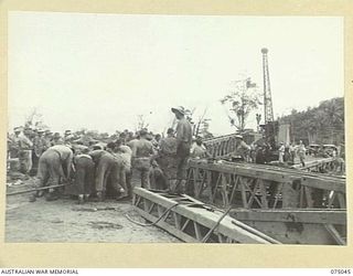 LAE, NEW GUINEA. 1944-08-09. TROOPS OF THE 20TH FIELD COMPANY, "JOCKEYING" A STEEL GIRDER INTO POSITION DURING THE BUILDING OF A NEW BRIDGE ACROSS THE BUTIBUM RIVER TO REPLACE THE OLD WOODEN ONE ..