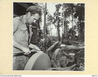 BUSU FOREST, LAE AREA, NEW GUINEA. 1944-07-26. AN AXE BEING GROUND AT THE 2/3RD FORESTRY COMPANY, ROYAL AUSTRALIAN ENGINEERS, DURING PREPARATIONS FOR TREE FELLING