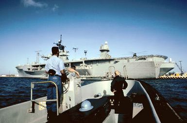 A motor whale boat from the amphibious command ship USS BLUE RIDGE (LCC-19) returns to the ship. Alongside the BLUE RIDGE is a fuel barge