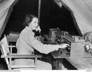 PALMALMAL PLANTATION, JACQUINOT BAY, NEW BRITAIN. 1945-07-17. PRIVATE A. ANDERSON, ON DUTY AT THE SWITCHBOARD BEFORE GOING TO A SPECIAL DANCE HELD AT THE AUSTRALIAN ARMY MEDICAL WOMEN'S SERVICE ..