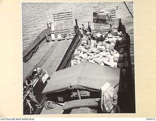 BORAM, NEW GUINEA, 1945-08-06. SUPPLIES BEING LOWERED FROM THE OCEAN FREIGHTER TO AUSTRALIAN LANDING CRAFT WORKING WITH HQ COMMAND, AUSTRALIAN ARMY SERVICE CORPS, 6 DIVISION, FOR TRANSPORT TO THE ..