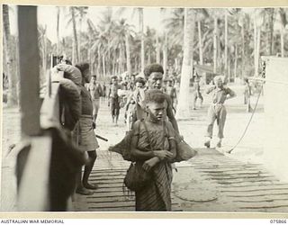 ALEXISHAFEN NORTH, NEW GUINEA. 1944-09-01. NATIVE FAMILIES FROM THE HILLS COMING ABOARD A BARGE FOR TRANSPORT TO ADOMOSIN ISLAND IN SEK HARBOUR FOR A BIG NATIVE SING SING