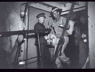 SYDNEY, NSW 1945-08-07. MAJOR GENERAL E C P PLANT, GENERAL OFFICER COMMANDING NSW LINES OF COMMUNICATION AREA, STANDING AT THE TOP OF THE GANGWAY AS AUSTRALIAN ARMY PERSONNEL FROM NEW GUINEA, DUE ..