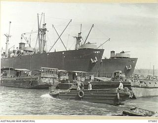 LAE, NEW GUINEA. 1944-09-08. A BUSY SCENE OF THE WATERFRONT SHOWING AN AMERICAN, AMPHIBIOUS "DUKW", LANDING BARGES AND "LIBERTY" SHIPS ANCHORED AND DISCHARGING THEIR CARGO