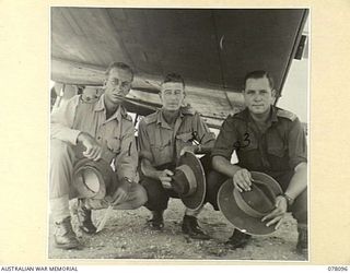 TOROKINA, BOUGAINVILLE ISLAND. 1944-12-15. AUSTRALIAN ARMY OFFICERS SHELTERING FROM THE TROPICAL SUN UNDER THE MAINPLANE OF THE AIRCRAFT WHICH IS TO CARRY THE GENERAL OFFICER COMMANDING FIRST ..