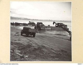 BORAM BEACH, NEW GUINEA. 1945-08-06. A GENERAL VIEW OF TRUCKS OF HEADQUARTERS COMMAND, AUSTRALIAN ARMY SERVICE CORPS, 6 DIVISION CARRYING SUPPLIES FROM AN AUSTRALIAN LANDING CRAFT. THE SUPPLIES ..