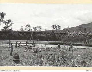 EVAPIA RIVER, NEW GUINEA, 1944-03-15. TROOPS FROM THE 2/4TH FIELD COMPANY, ROYAL AUSTRALIAN ENGINEERS RIG GEAR AND TACKLE TO ERECT THE LARGE MAIN SUPPORT FOR THE SUSPENSION BRIDGE ACROSS THE EVAPIA ..