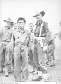 DUMPU, NEW GUINEA. 1944-04-19. ONE OF FOUR JAPANESE PRISONERS OF WAR, ESCORTED BY CORPORAL A.S. LUKEMAN (1), 11TH DIVISION PROVOST COMPANY, WAITING INTERROGATION BY INTELLIGENCE OFFICERS AT ..