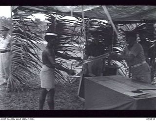 LAE, NEW GUINEA, 1946-02-14. AT A SPECIAL PARADE, MAJOR GENERAL B.M. MORRIS, GENERAL OFFICER COMMANDING AUSTRALIAN NEW GUINEA ADMINISTRATIVE UNIT, PRESENTED GIFTS (FRAMED COLOURED PHOTOGRAPHS OF ..