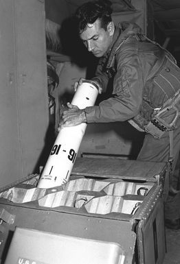 A member of Naval Air Reserve Patrol Squadron 64 (VP-64) on active duty training inserts a sonobuoy into its dispenser chute in a P-3 Orion aircraft