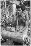 Man beating on a log as if he were playing an 'o'o slitgong