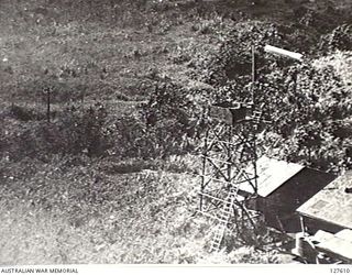 VUNAKANOU, NEW GUINEA. 1943-12-10. VIEW FROM FIFTH AIR FORCE, UNITED STATES ARMY AIR FORCE BOMBER, OF THE AIRSTRIP CONTROL TOWER, LEFT OF PHOTO TELEPHONE LINES LEADING TO THE CITY. "PARAFRAGS" CAN ..