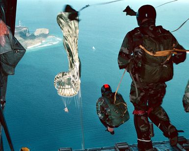 During a Sequential CRRC (Combat Rubber Raiding Craft) training, members of Explosive Ordnance Disposal Mobile Unit FIVE, perform a static line jump from a US Air Force C-130 over Apra Harbor, Guam