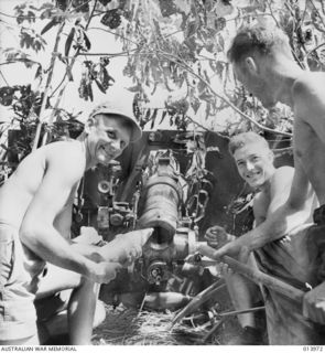 1942-12-31. BUNA. AN AUSTRALIAN MOUNTAIN BATTERY SHELLS BUNA. GUNNER A. DIXON (N.S.W.) HAS A SHELL READY FOR GUNNER A.E. BARRETT (N.S.W.) TO RAM HOME. (NEGATIVE BY G. SILK)