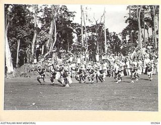 TOROKINA, BOUGAINVILLE. 1945-06-10. NATIVE SING-SING AT THE WEBB ROAD COMPOUND ON THE NUMA NUMA TRAIL WHICH WAS ATTENDED BY A LARGE NUMBER OF TROOPS. THE NATIVES PARTICIPATING ARE ATTACHED TO ..