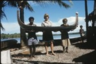 Frances Harwood and two men holding a miniature canoe