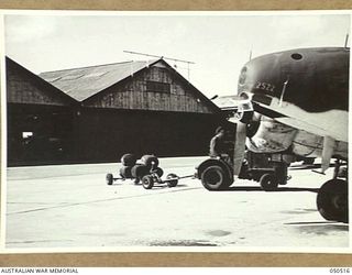 LAVERTON, VIC. 1943-04. HARMLESS SUPPLY CONTAINERS INSTEAD OF BOMBS. THE CONTAINERS WHICH ARE BEING USED IN AN EXPERIMENTAL SUPPLY DROPPING PROJECT, ARE SEEN HERE BEING LOADED INTO THE AIRCRAFT IN ..