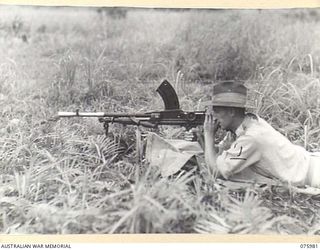 LAE, NEW GUINEA. 1944-09-13. VX85013 LIEUTENANT-COLONEL N.R. FORREST, ASSISTANT GENERAL OF THE ORDNANCE (E) HEADQUARTERS, NEW GUINEA FORCE TESTING THE MODIFIED BREN GUN. AMONG THE MODIFICATIONS ..