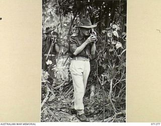 GUSIKA, NEW GUINEA, 1944-03-16. NX151704 LIEUTENANT J. SCOTT-STEVENSON, SECOND IN CHARGE OF THE SIGNALS SECTION, 4TH INFANTRY BRIGADE, OPERATING A SCR 536, (SET COMPLETE RADIO), FOLLOWED BY VX35038 ..