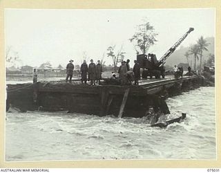 LAE, NEW GUINEA. 1944-08-09. TROOPS OF THE 20TH FIELD COMPANY, USING A MOBILE CRANE TO CLEAR AWAY FLOOD DEBRIS FROM THE PILE PIERS OF THE BUTIBUM BRIDGE BEFORE COMMENCING THE REBUILDING OPERATIONS