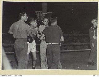 BOSLEY FIELD, TOROKINA, BOUGAINVILLE. 1945-04-21. KID DELANEY, 2 AUSTRALIAN WATERCRAFT COMPANY (1), STRUGGLES WITH HIS SECONDS TO REACH HIS OPPONENT V.A. MCKINZIE, UNITED STATES NAVAL BASE, AN ..