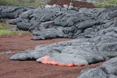 Close u of red hot lava flowing on a dirt road, a result of the Kilauea Volcano eruption and lava flow in 2014.
