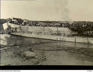 But, New Guinea. May 1945. LTD Australian-built barge 027 drawn up on the beach, full of supplies and equipment, including vehicles, transported from Aitape for the troops