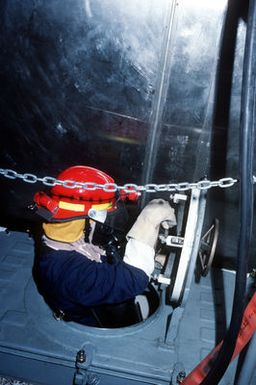 A damage control sailor is shown passing through the escape shuttle in the center of an X-ray hatch during a damage control and fire drill on board the guided missile cruiser USS PORT ROYAL (CG-73). The ship and her crew went to sea off Hawaii and are performing numerous fire drills in preparation for next month's operational propulsion plant exam (OPPE)