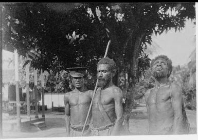 Policeman and two bush men, one holding a staff, Salamaua, New Guinea, 1937 / Sarah Chinnery