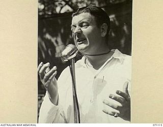 KILIGIA, NEW GUINEA, 1944-03-15. NX37475 LIEUTENANT R. DAWE, OFFICER COMMANDING 3RD ARMOURED DIVISION CONCERTY PARTY, GIVING HIS POPULAR IMITATION OF RICHARD TAUBER AT A REHEARSAL