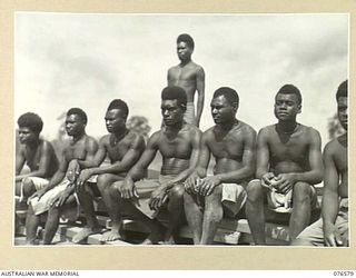 HOSKINS, NEW BRITAIN. 1944-10-09. NEW BRITAIN NATIVE BOYS WAITING TO COMMENCE WORK AT THE CAMP OF THE 36TH INFANTRY BATTALION