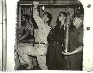 AT SEA. 1944-08/09. RATINGS WORKING IN THE 4" GUN MAGAZINE ABOARD THE RAN CORVETTE, GEELONG DURING GUNNERY PRACTICE AS THE VESSEL PROCEEDS ALONG THE COAST OF NEW GUINEA