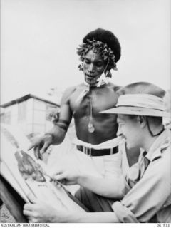 KILA KILA, PAPUA, NEW GUINEA. 1943-12-25. A RORO TRIBESMAN, OANE, SON OF OA, COMMENTS APPROVINGLY ON A PAINTING OF A FELLOW TRIBESMAN BY VX93433 CAPTAIN W. A. DARGIE, WAR ARTIST, MILITARY HISTORY ..