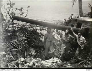 MOMOTE, LOS NEGROS ISLAND, ADMIRALTY ISLANDS. 1944-03-29. RAAF PERSONNEL BESIDE A JAPANESE NAVAL GUN. LEFT TO RIGHT: PILOT OFFICER C. BURLEY OF SA; FLIGHT SERGEANT (FLT SGT) T. BOEHM OF SA; FLT SGT ..