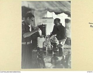 SOUTH ALEXISHAFEN, NEW GUINEA. 1944-08-08. NX126019 LIEUTENANT F.H. KILMINSTER (1) AND NX81707 STAFF SERGEANT A.H. BERESFORD (2) WORKING IN THE DISPENSARY OF THE 111TH CASUALTY CLEARING STATION