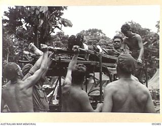 BOUGAINVILLE. 1945-05-21. TROOPS OF 58/59 INFANTRY BATTALION LIFTING PRIVATE L. FULLER (3), WHO WAS WOUNDED BY JAPANESE ARTILLERY SOUTH OF THE HONGORAI RIVER, ONTO A JEEP AMBULANCE FOR TRANSPORT TO ..