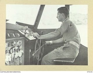 NORTH ALEXISHAFEN, NEW GUINEA. 1944-08-18. THE SKIPPER OF THE MEDICAL LAUNCH, AM1567 OF THE NEW GUINEA SEA AMBULANCE TRANSPORT COMPANY, NX99720 SAPPER H. AULD (1) KEEPING A CAREFUL LOOK-OUT FOR ..