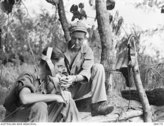 BOUGAINVILLE, SOLOMON ISLANDS. 1944-12-09. PRIVATE R.G. ALLDER, HQ COMPANY, 15 INFANTRY BATTALION, (1), RECEIVES A LIGHT FROM PTE L.S. RUSSELL, 182 INFANTRY REGIMENT, UNITED STATES ARMY, (2), AS ..